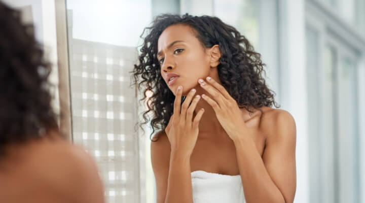 Woman looking at skin in mirror