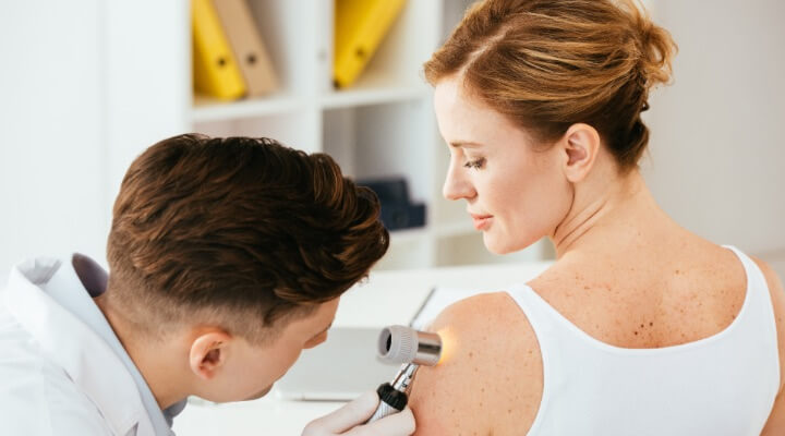 Doctor examining mole on a woman's shoulder